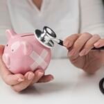 person putting stethoscope piggy bank